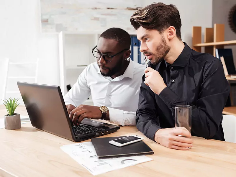 two business person looking at laptop and discussing