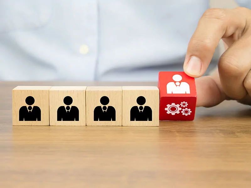 5 wooden cubes with user icon on it and a person picking up the red cube