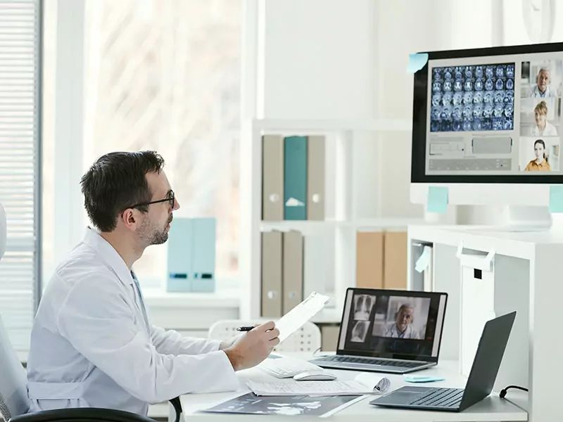 doctor holding a report and looking at screen and consulting patients